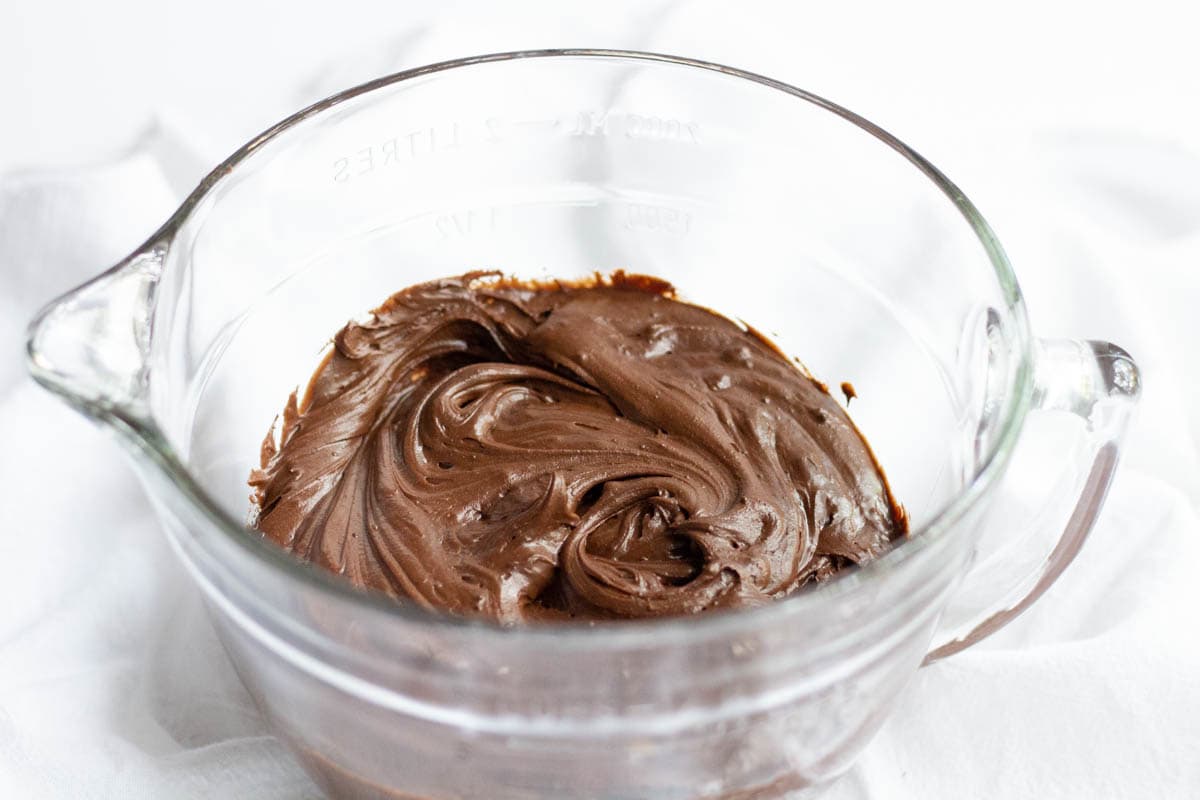 Chocolate fudge frosting inside of a large glass measuring cup
