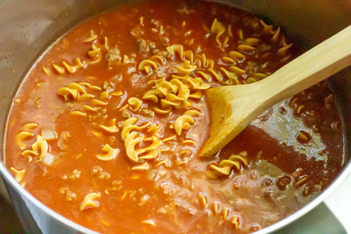 So Easy Tomato Beef Kluski | thewendthousekitchen.com All ingredients for tomato beef Kluski mixed together inside of a large sauce pan with a wooden spoon
