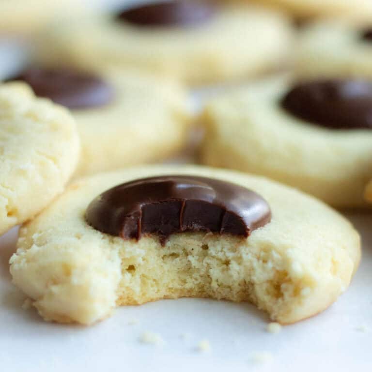 Chinese cookies on parchment with one cookie in the front with a bite taken out of it
