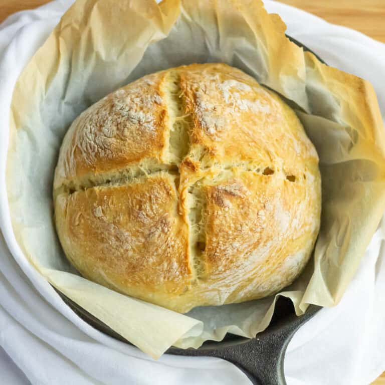 Crusty No knead bread in a cast iron pan with parchment