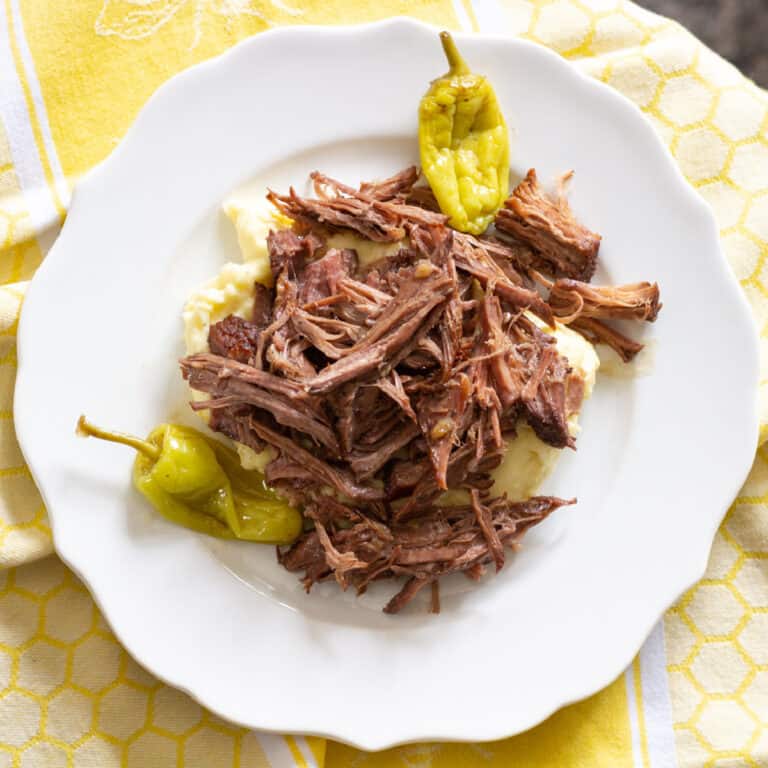 Crockpot Mississippi Pot Roast on a plate with pepperoncini peppers on the sides