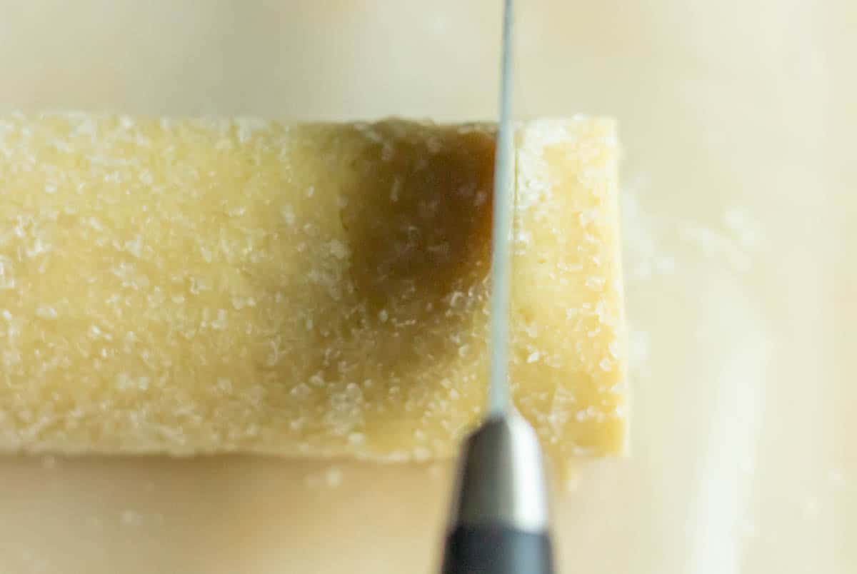 Old-Fashioned Butter Cookie Recipe | thewendthousekitchen.com Cutting cookie dough into slices from log of dough covered in sanding sugar.