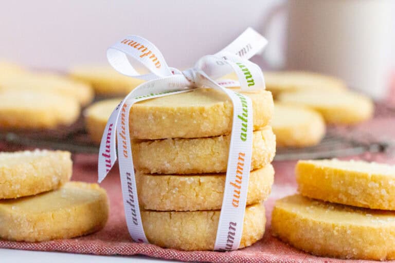 Butter cookies stacked and tied with a ribbon with other butter cookies next to and in the background.