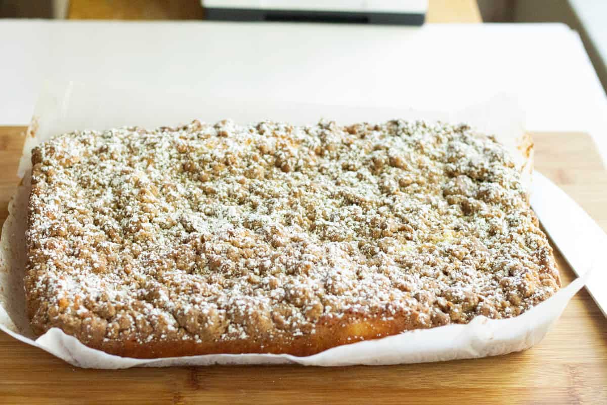 Baked cake garnished with powdered sugar cooling on parchment paper