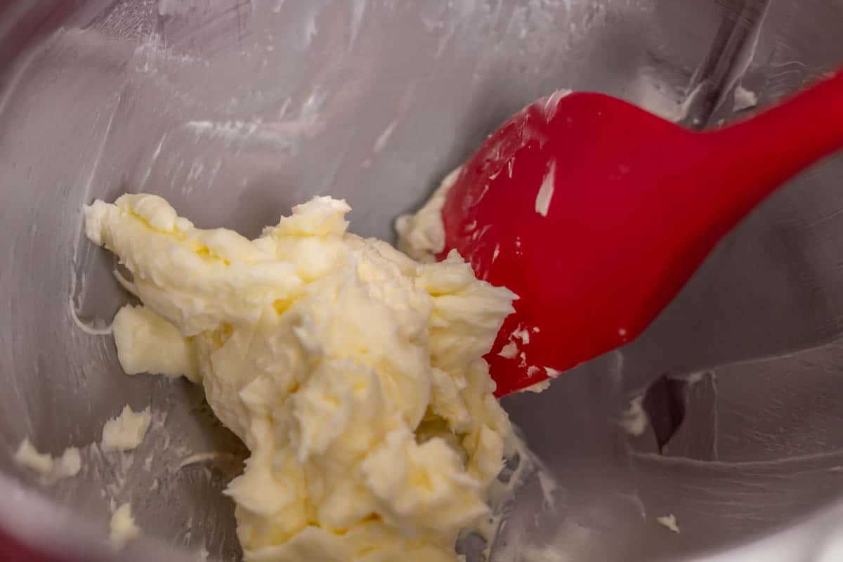 Whipped butter in the bowl of a stand mixer with a red rubber spatula