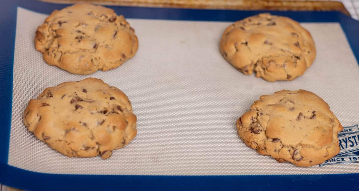 Four baked cookies on a Silpat on a cookie sheet