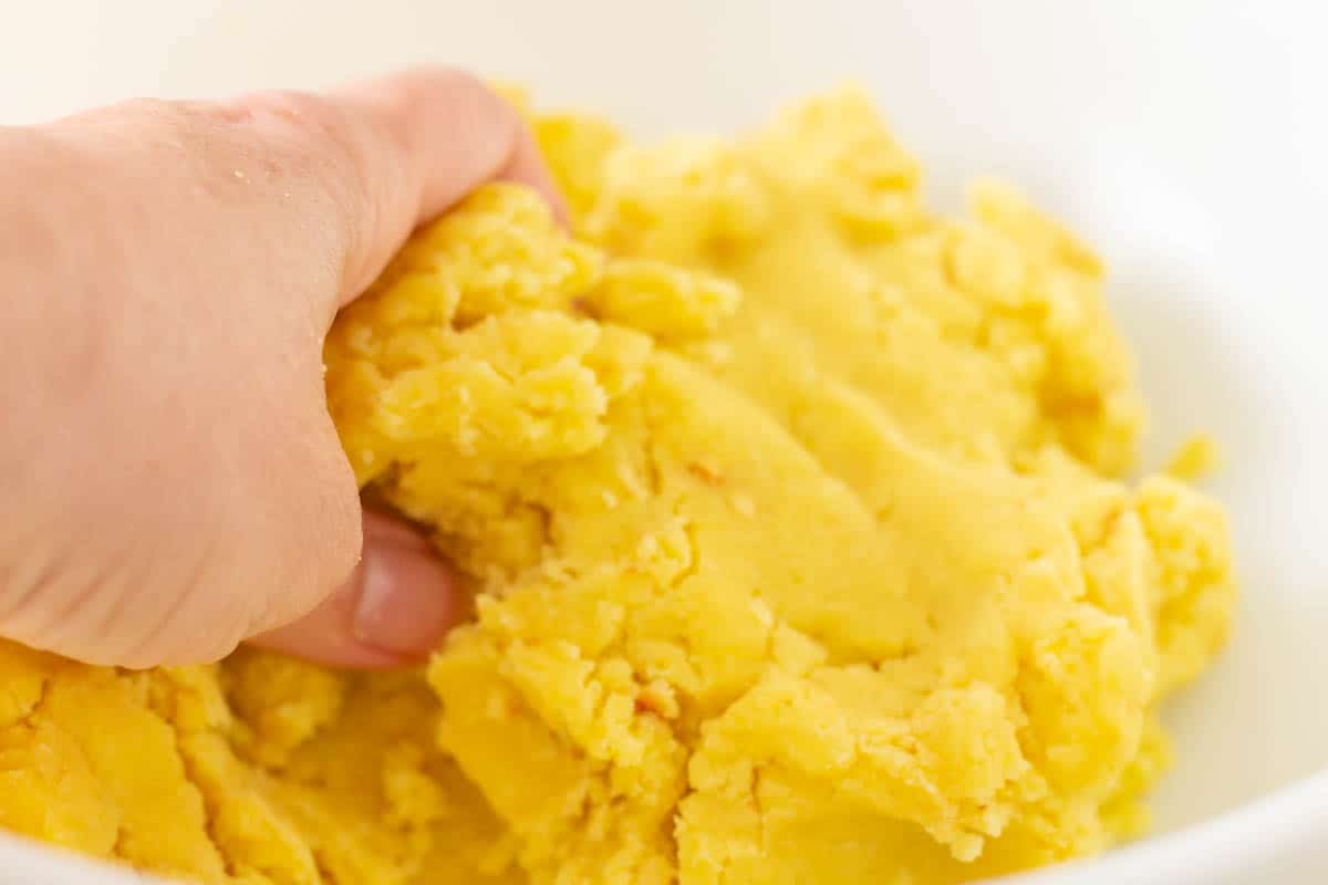Mixing cake and frosting with hands in a large mixing bowl