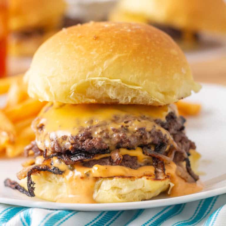 Cheeseburger on a brioche bun on a white plate with other cheeseburgers in the background