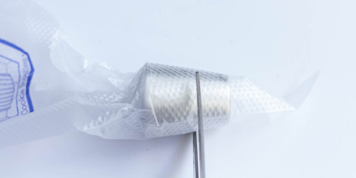 Using a scissor to mark on the piping tip where you are going to cut the piping bag