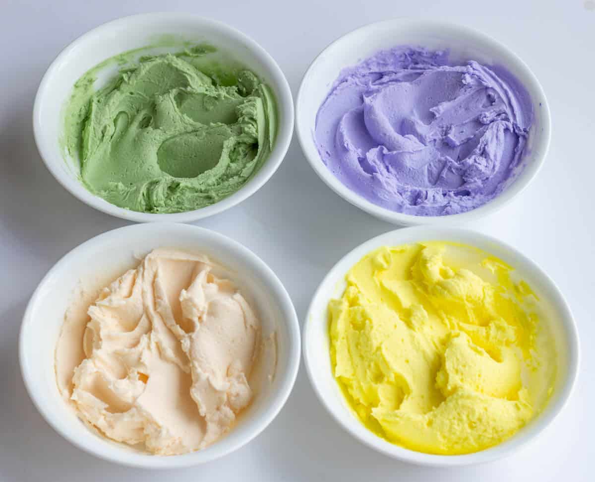 Green, lavender, ivory and yellow buttercream in individual white bowls