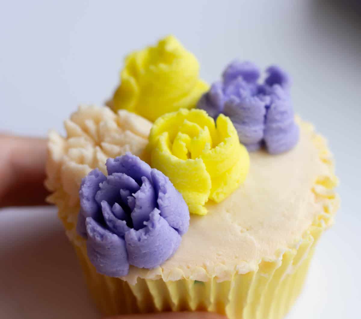 Five buttercream flowers added to an iced cupcake