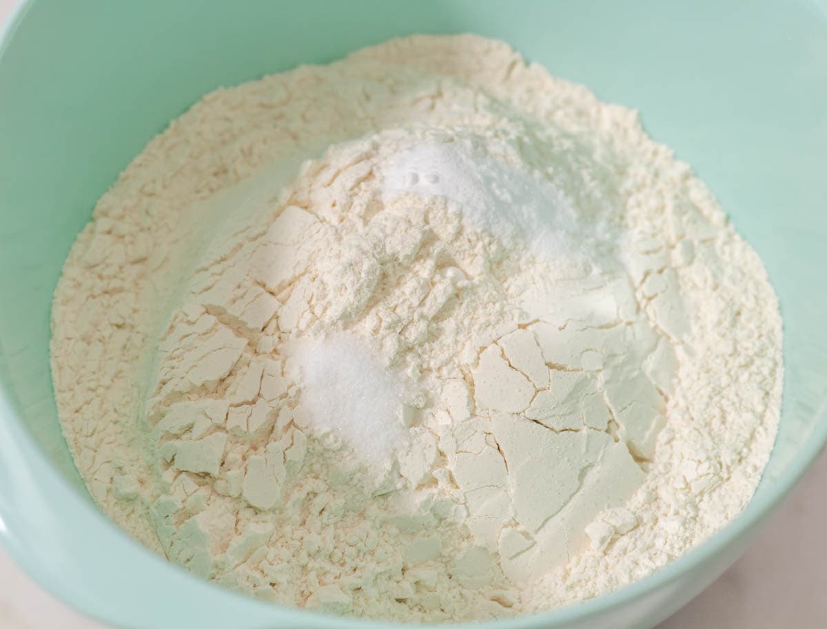 Flour, baking soda and salt added to a medium light aqua mixing bowl