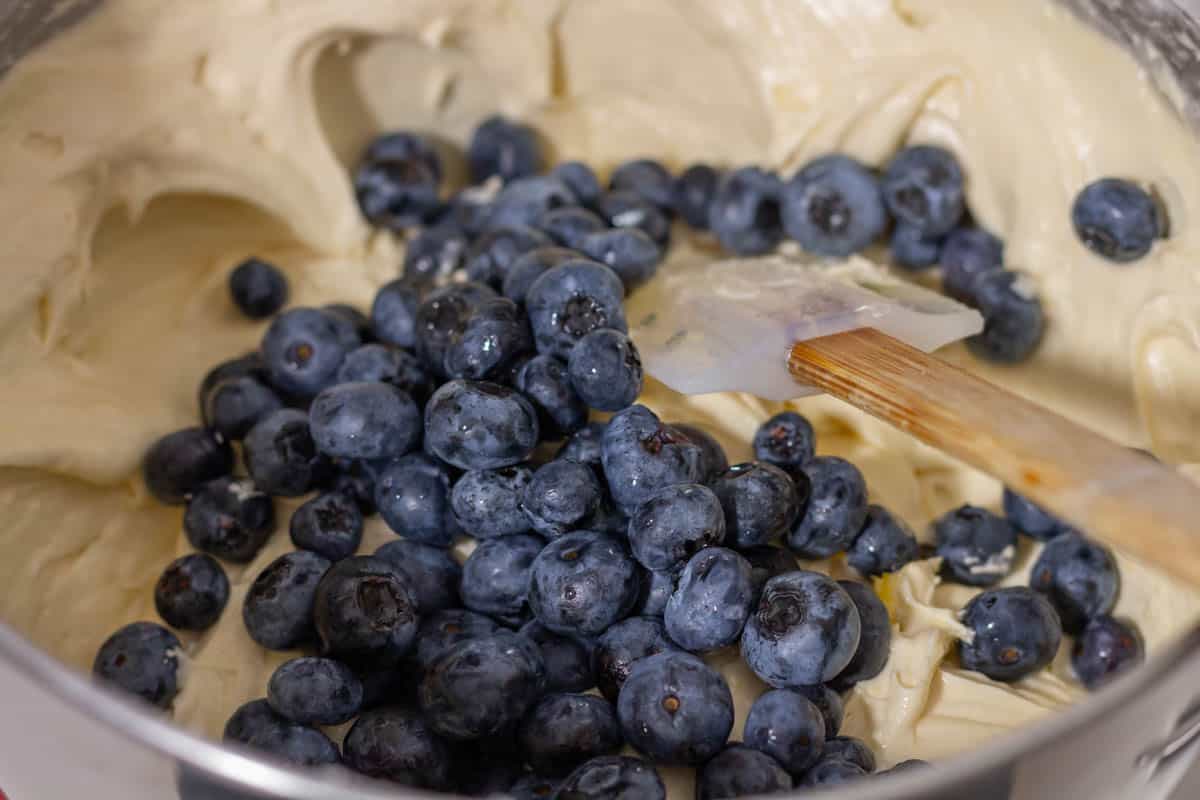 Blueberries added to the cake batter in the bowl of a stand mixer
