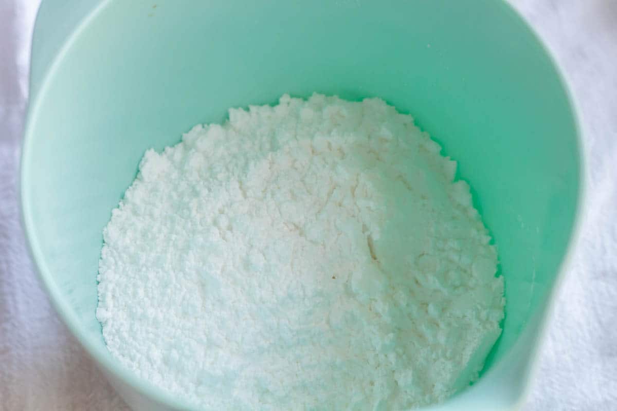 Powdered sugar added to a small light aqua mixing bowl