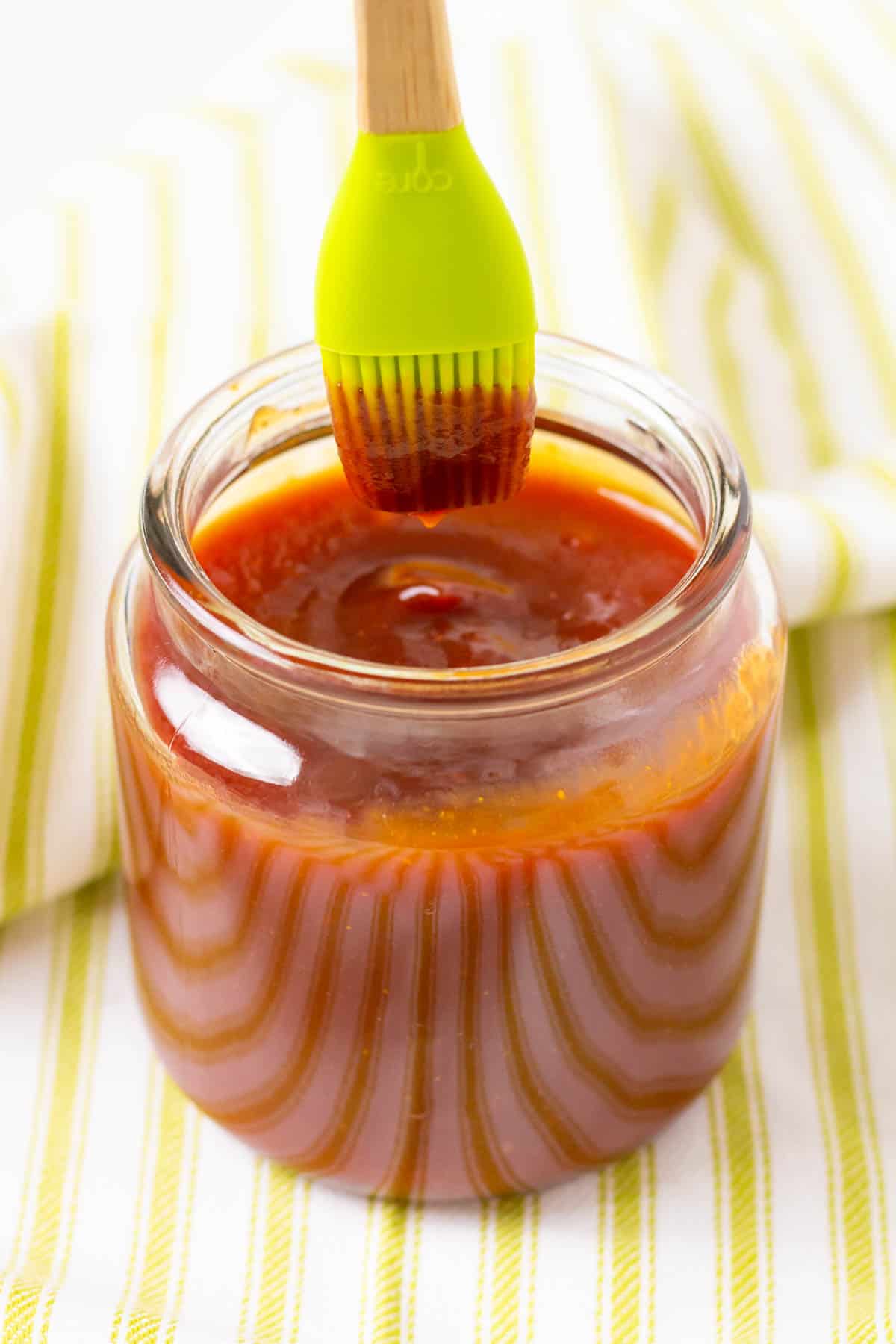 BBQ sauce on a green brush over a jar of BBQ sauce