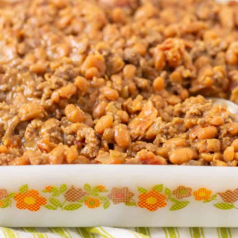Baked beans in a white baking dish with orange and brown flowers