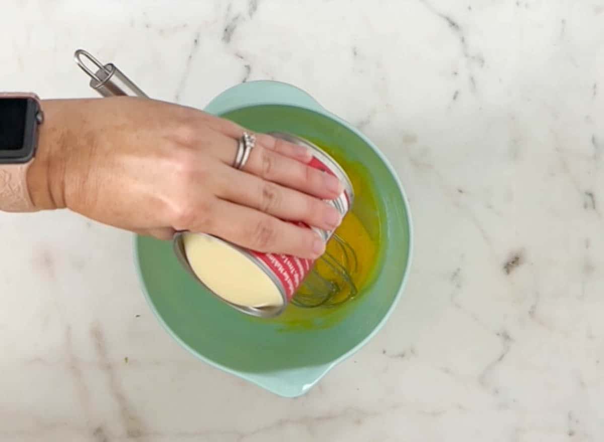 Pouring sweetened condensed milk into egg yolks and lime juice