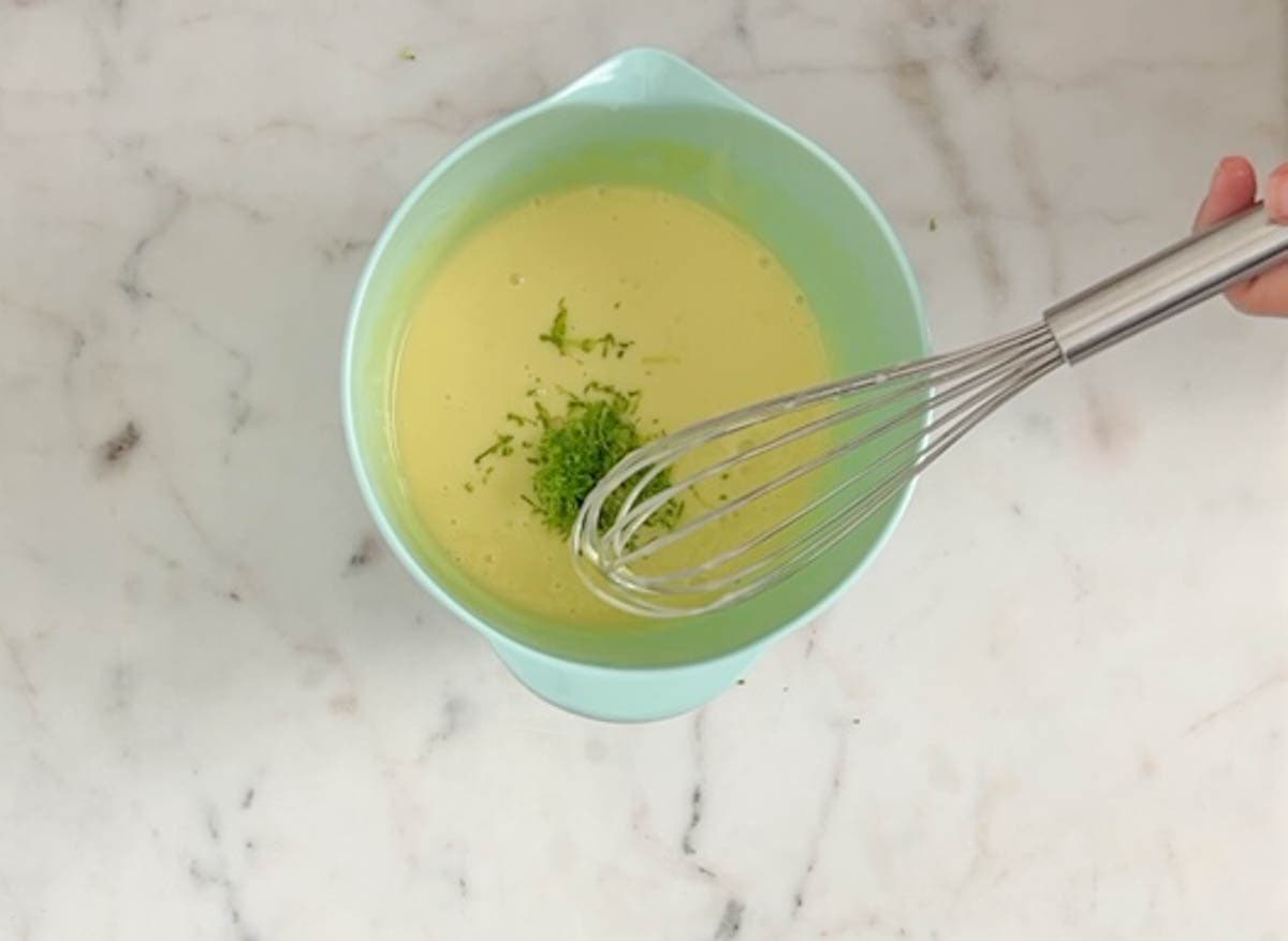 Lime zest added to key lime pie filling in a medium aqua bowl