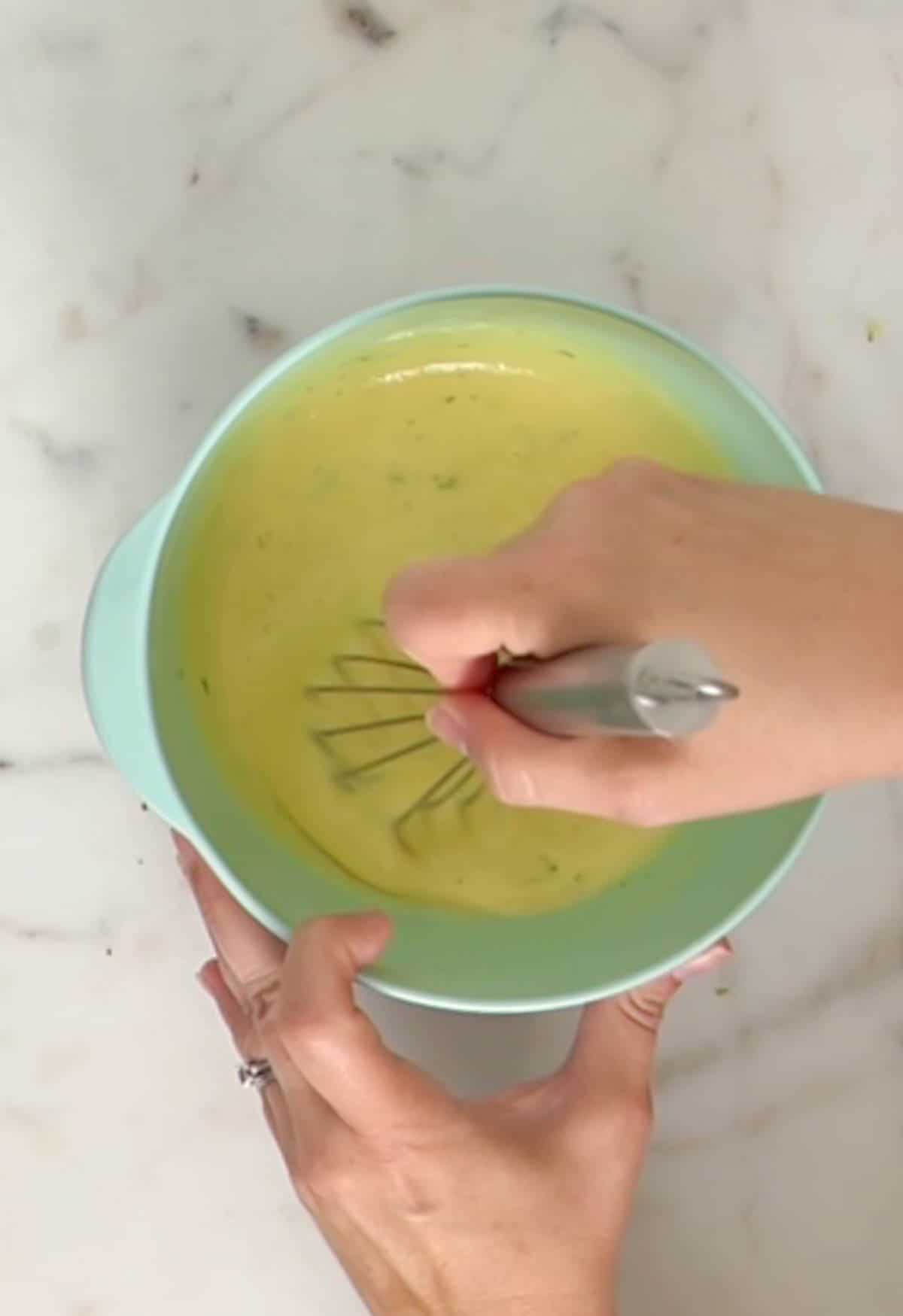 Mixing lime zest into key lime pie filling in a medium aqua mixing bowl