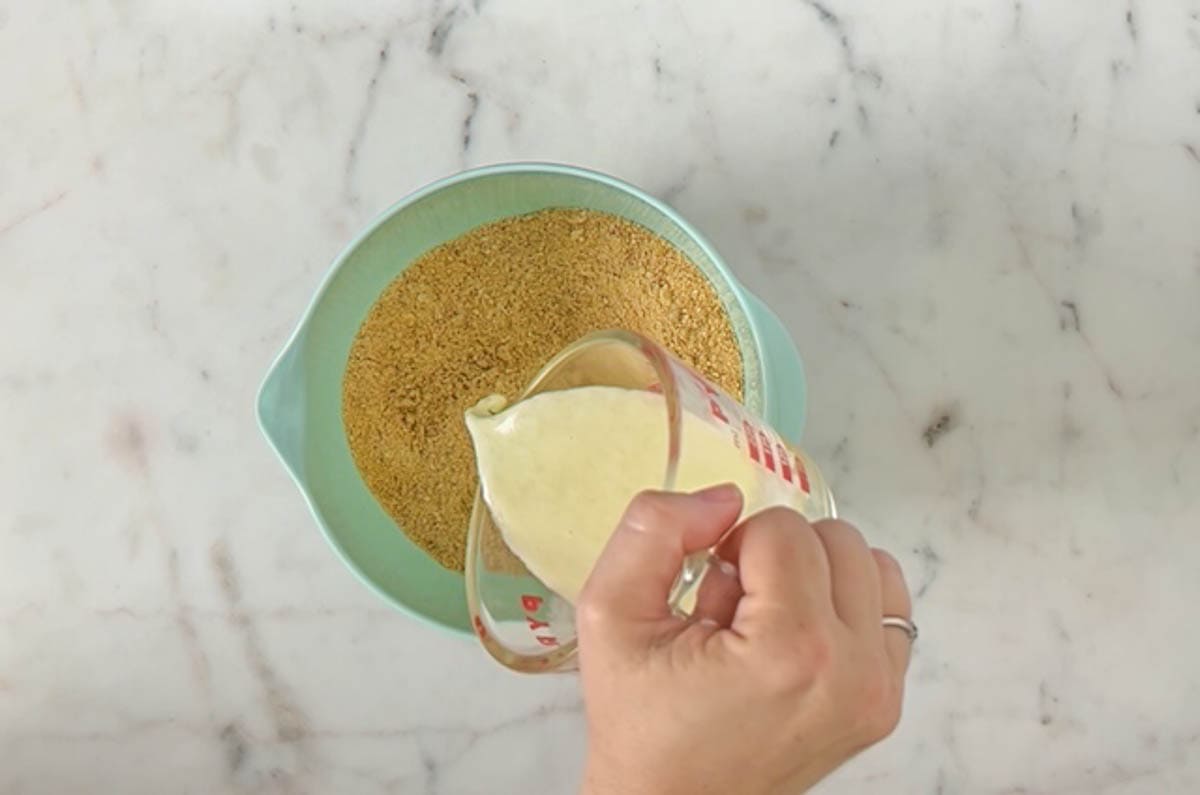 Pouring melted butter into crumb mixture