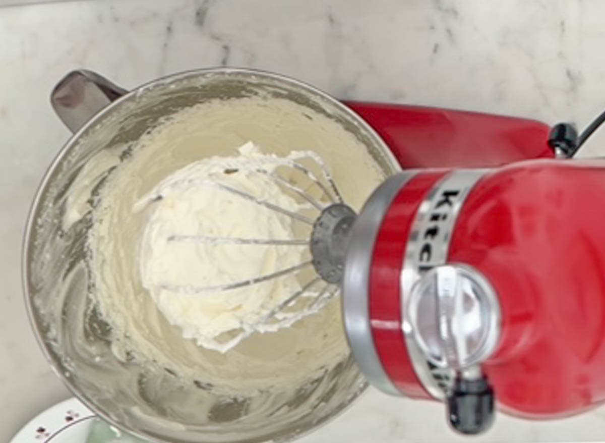 Whipped cream in the bowl of a red stand mixer