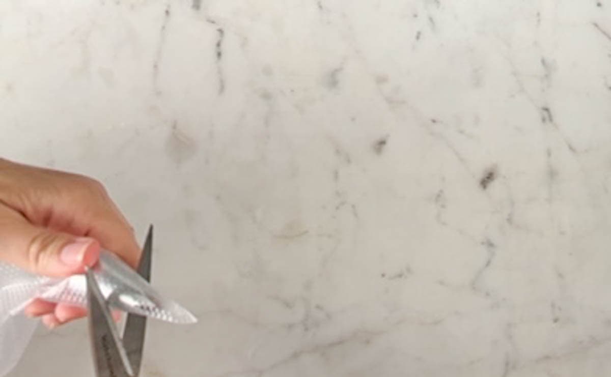 Marking a cutting line on a disposable pastry bag with a pair of scissors