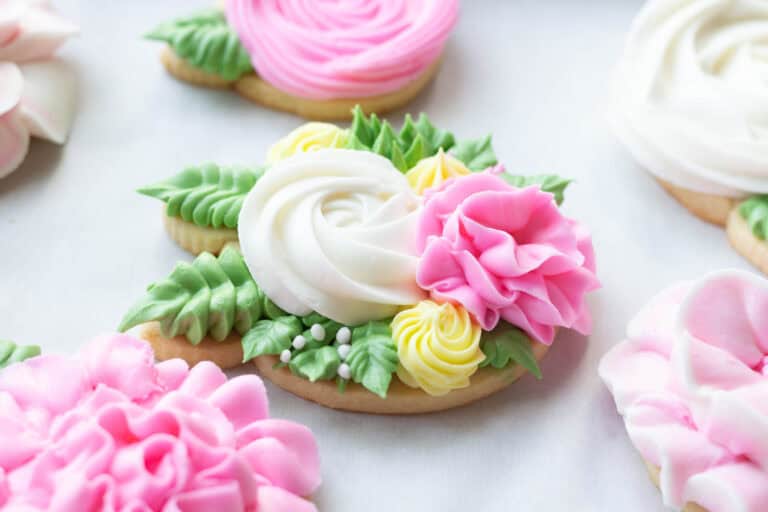 Pink, white and green royal icing flowers on sugar cookies.