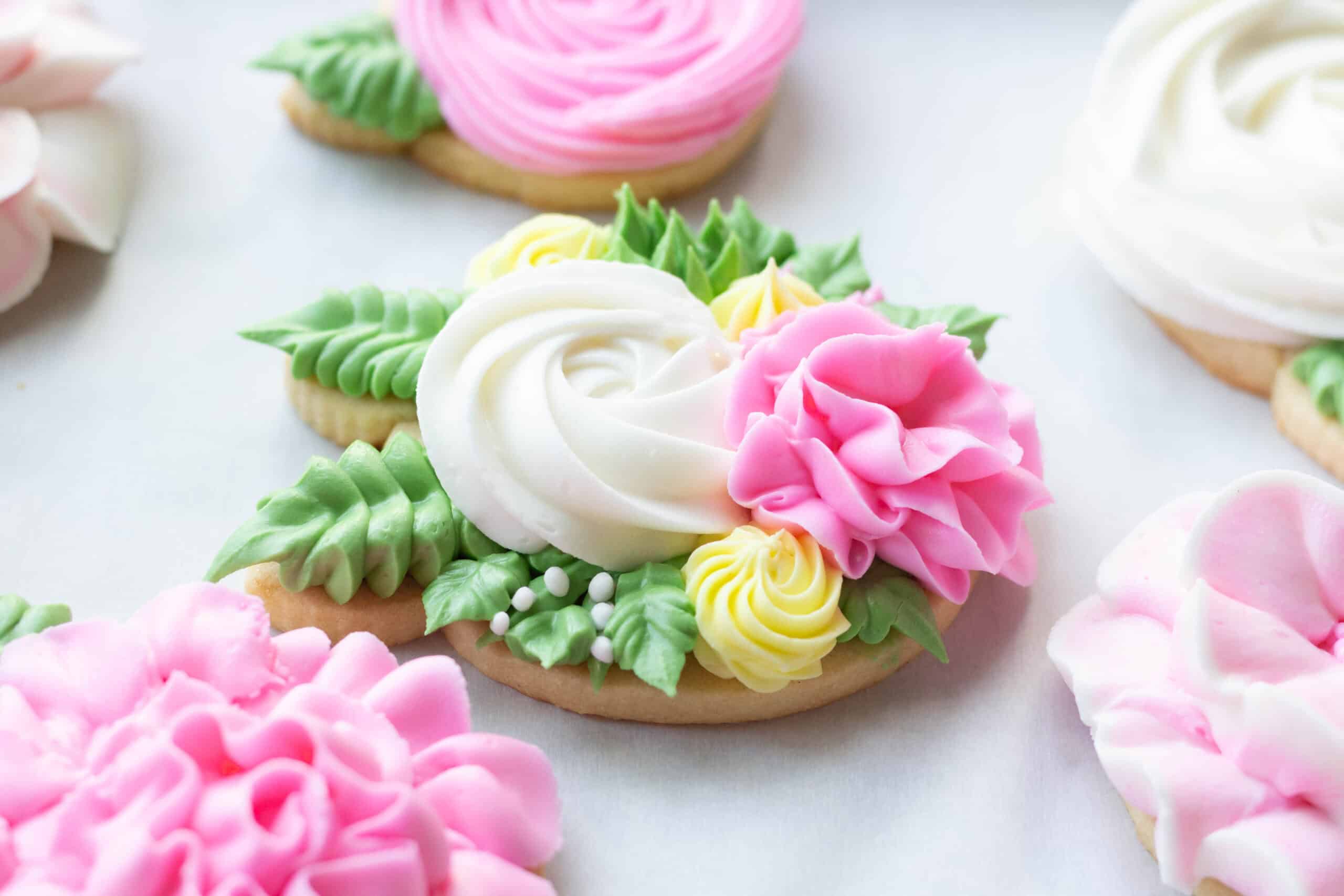 Pink, white and green royal icing flowers on sugar cookies.