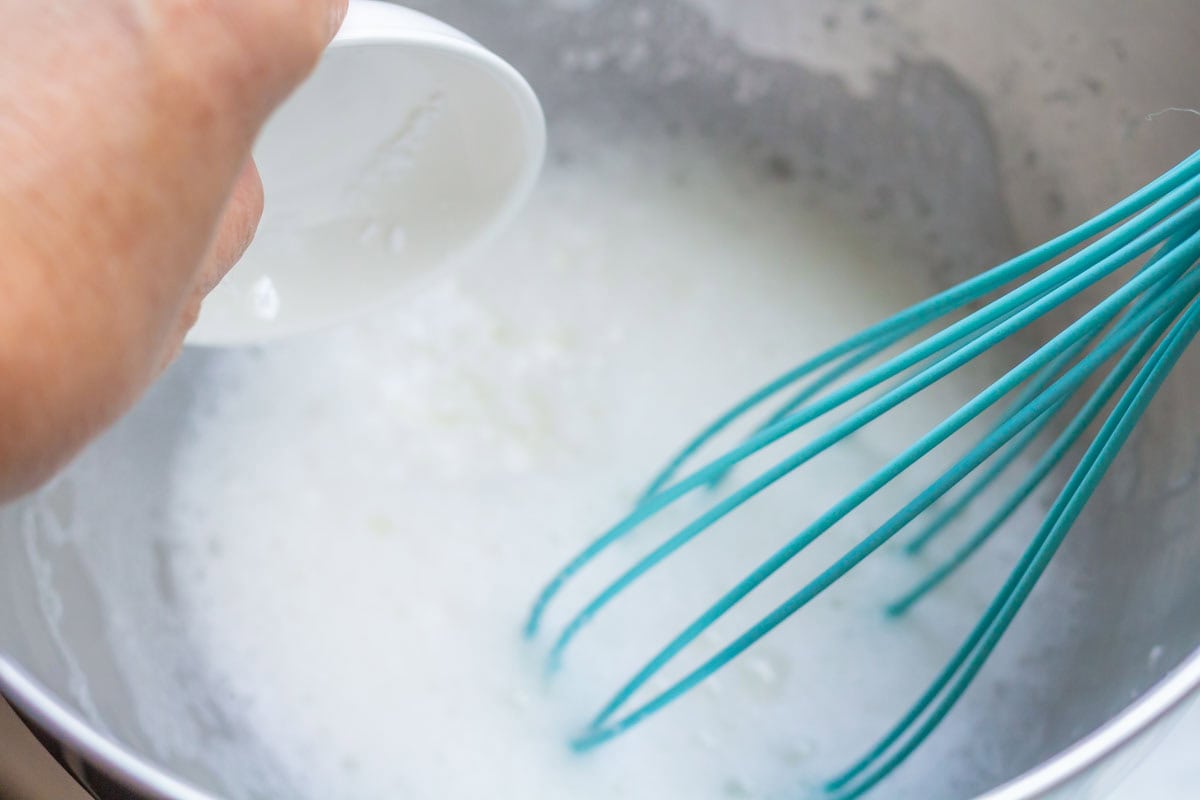 Royal Icing Recipe with Meringue Powder | thewendthousekitchen.com Pouring cream of tartar into the bowl of a stand mixer with water and meringue powder mixture and a wire whisk.