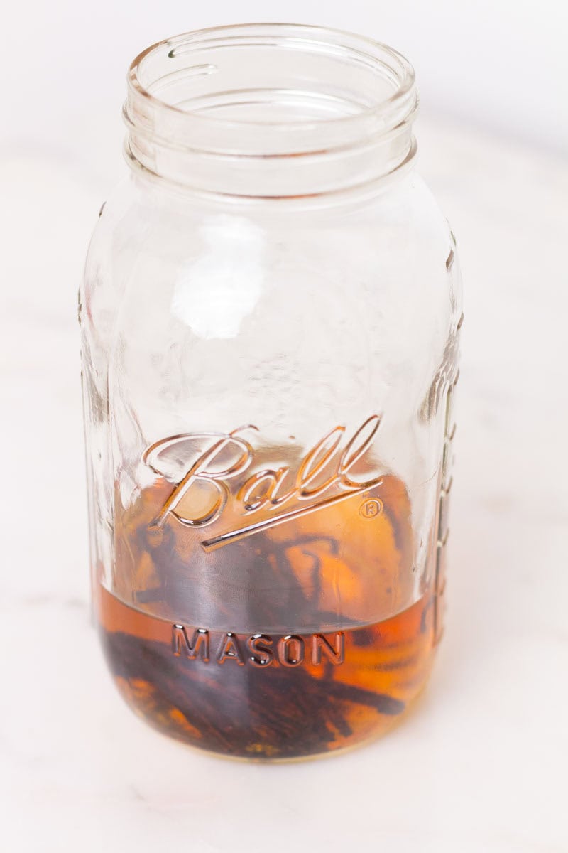 Easy Bourbon Vanilla Extract | thewendthousekitchen.com Bourbon and vanilla beans inside of a glass Mason jar.