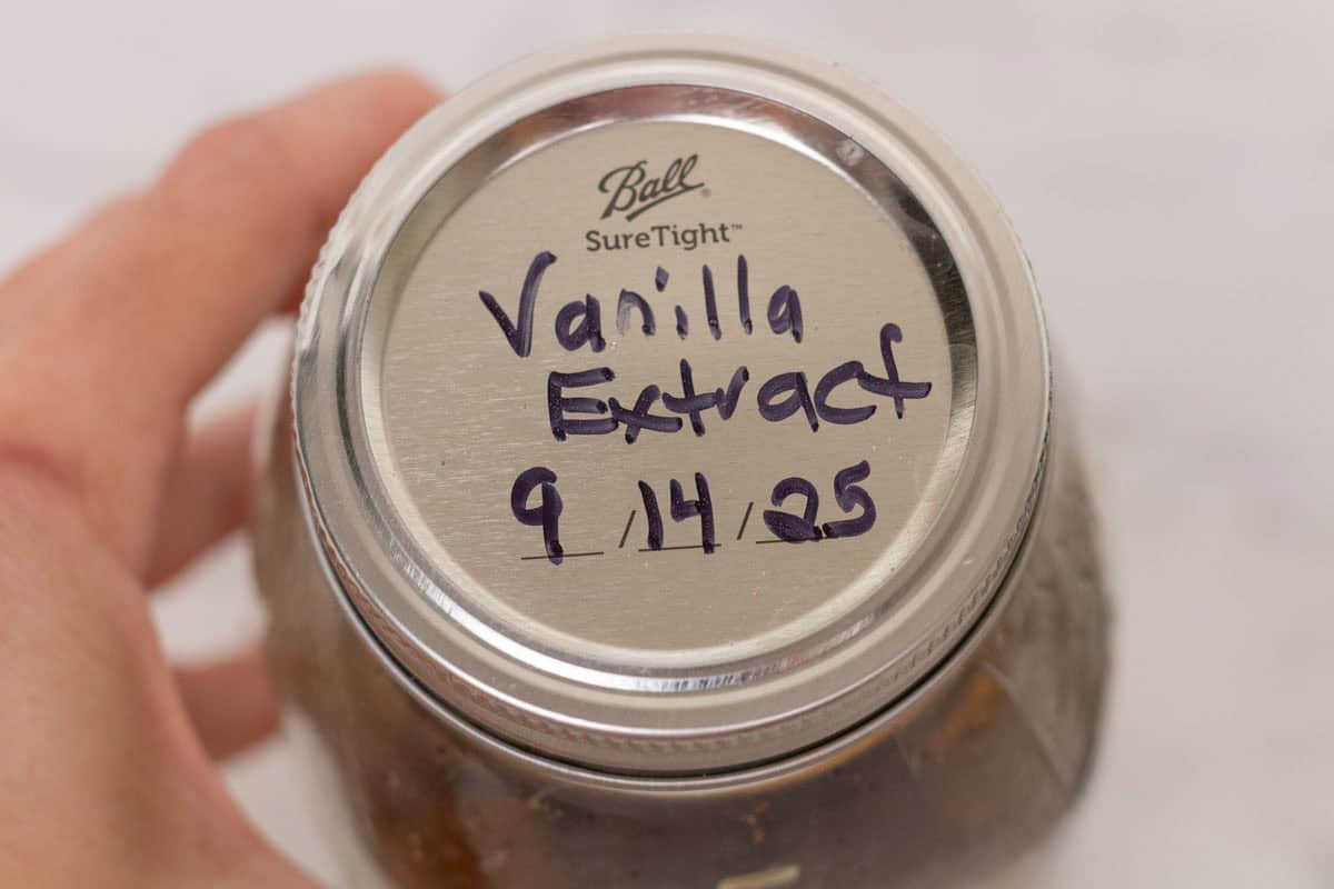 Easy Bourbon Vanilla Extract | thewendthousekitchen.com A labeled Mason jar lid that says, "Vanilla Extract, 9/14/25".