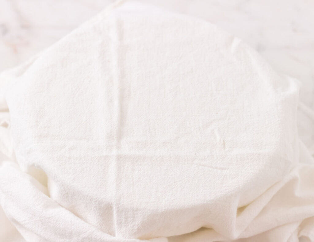 A large mixing bowl covered with a tea towel.