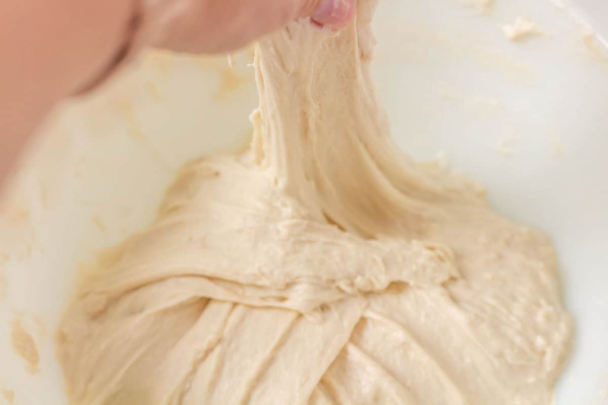 How To Make Artisan Sourdough Bread | thewendthousekitchen.com Stretching and pulling sourdough dough up with hands.