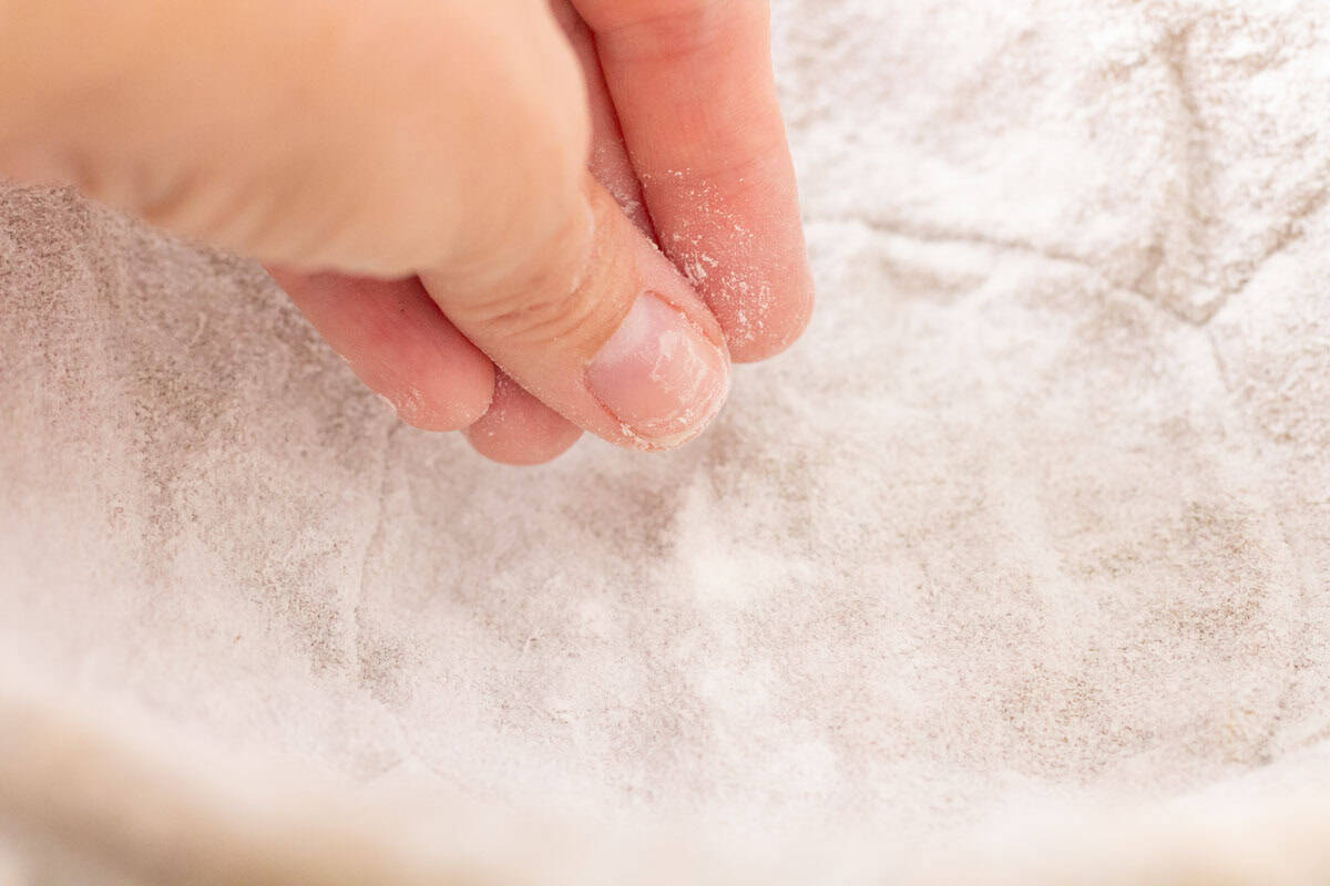 How To Make Artisan Sourdough Bread | thewendthousekitchen.com Sprinkling rice flour into a lined banneton bowl.