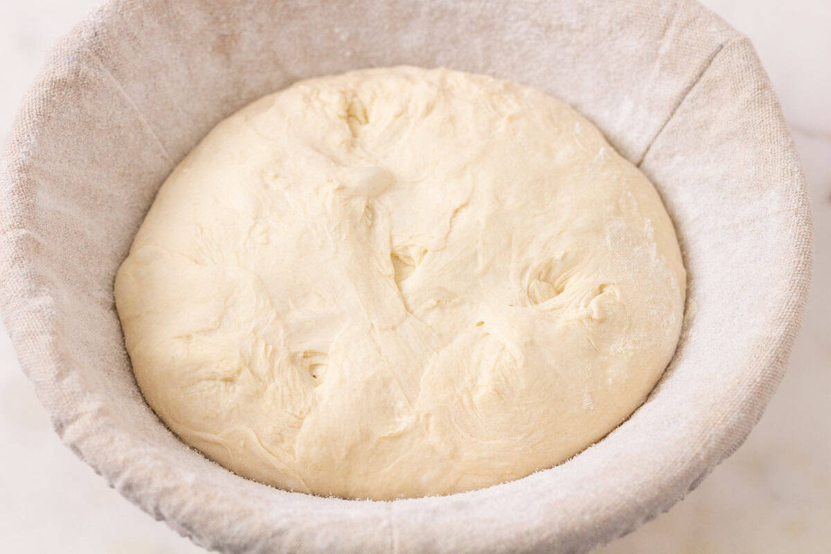 How To Make Artisan Sourdough Bread | thewendthousekitchen.com Sourdough inside of a floured and lined banneton bowl seam-side up.