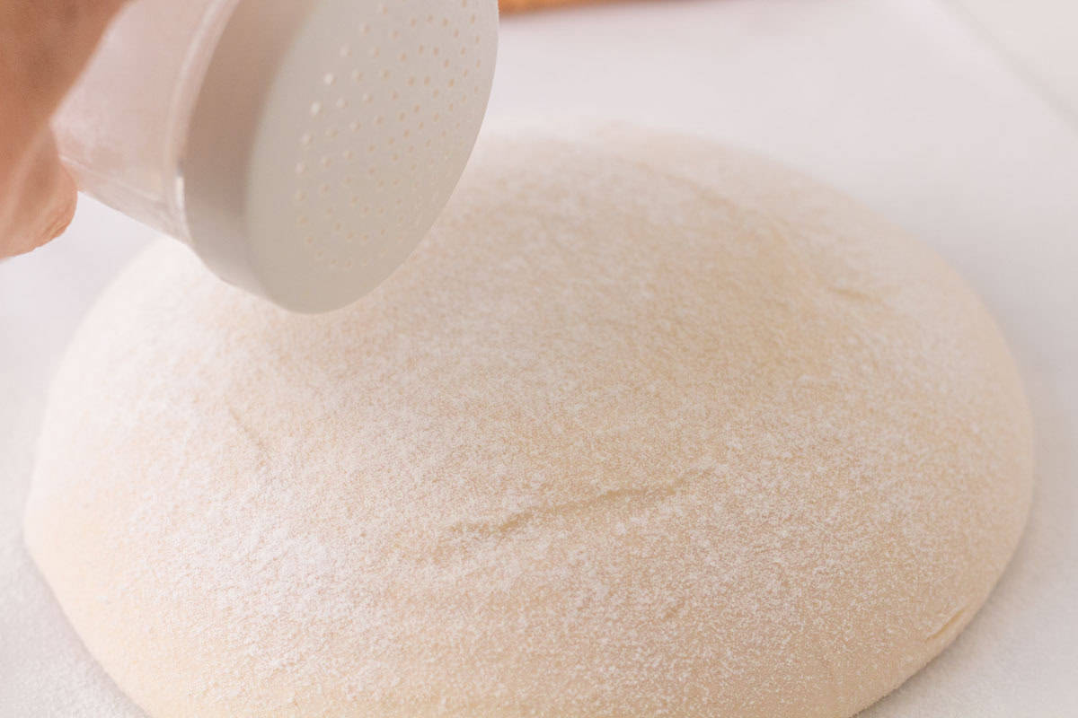 How To Make Artisan Sourdough Bread | thewendthousekitchen.com Sprinkling rice flour onto sourdough sitting on parchment paper.