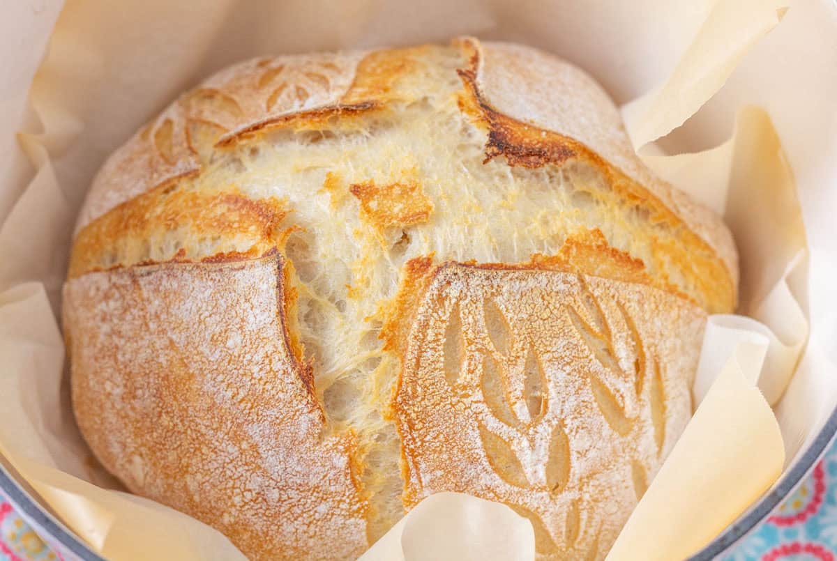 How To Make Artisan Sourdough Bread | thewendthousekitchen.com Baked sourdough loaf inside of a parchment-lined Dutch oven.