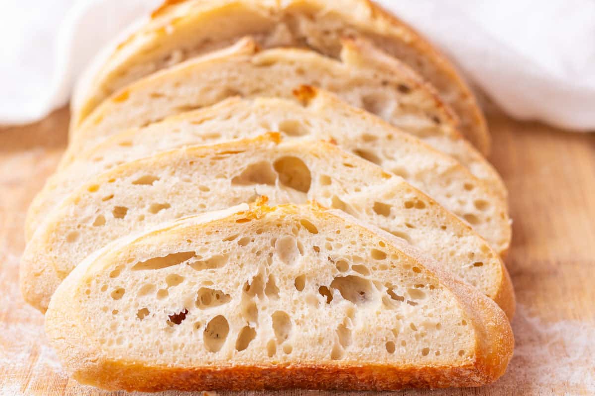How To Make Artisan Sourdough Bread | thewendthousekitchen.com Sliced sourdough bread on a cutting board with a tea towel in the background.