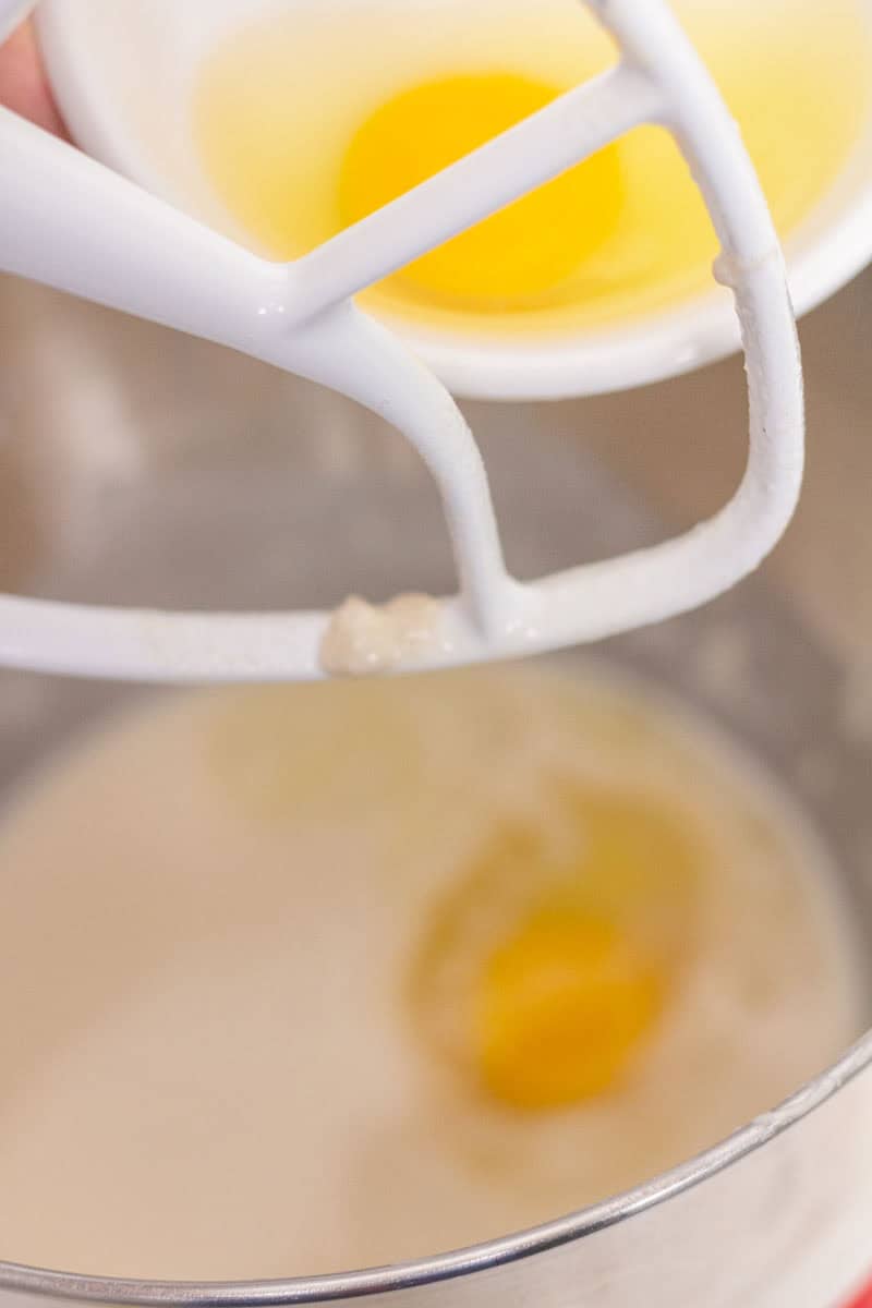 Sour Dough Discard Cinnamon Rolls | thewendthousekitchen.com Adding eggs to the bowl of a stand mixer with cinnamon roll ingredients.