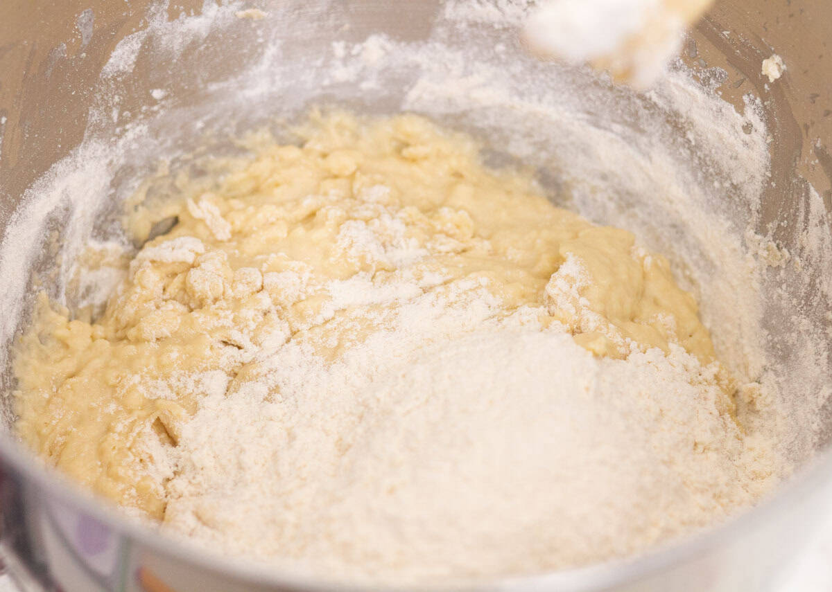 Sour Dough Discard Cinnamon Rolls | thewendthousekitchen.com Adding flour to cinnamon roll ingredients in the bowl of a stand mixer.