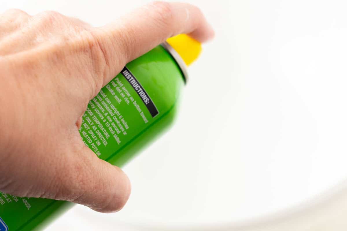 Sour Dough Discard Cinnamon Rolls | thewendthousekitchen.com Spraying non-stick cooking spray into a large Pyrex bowl.