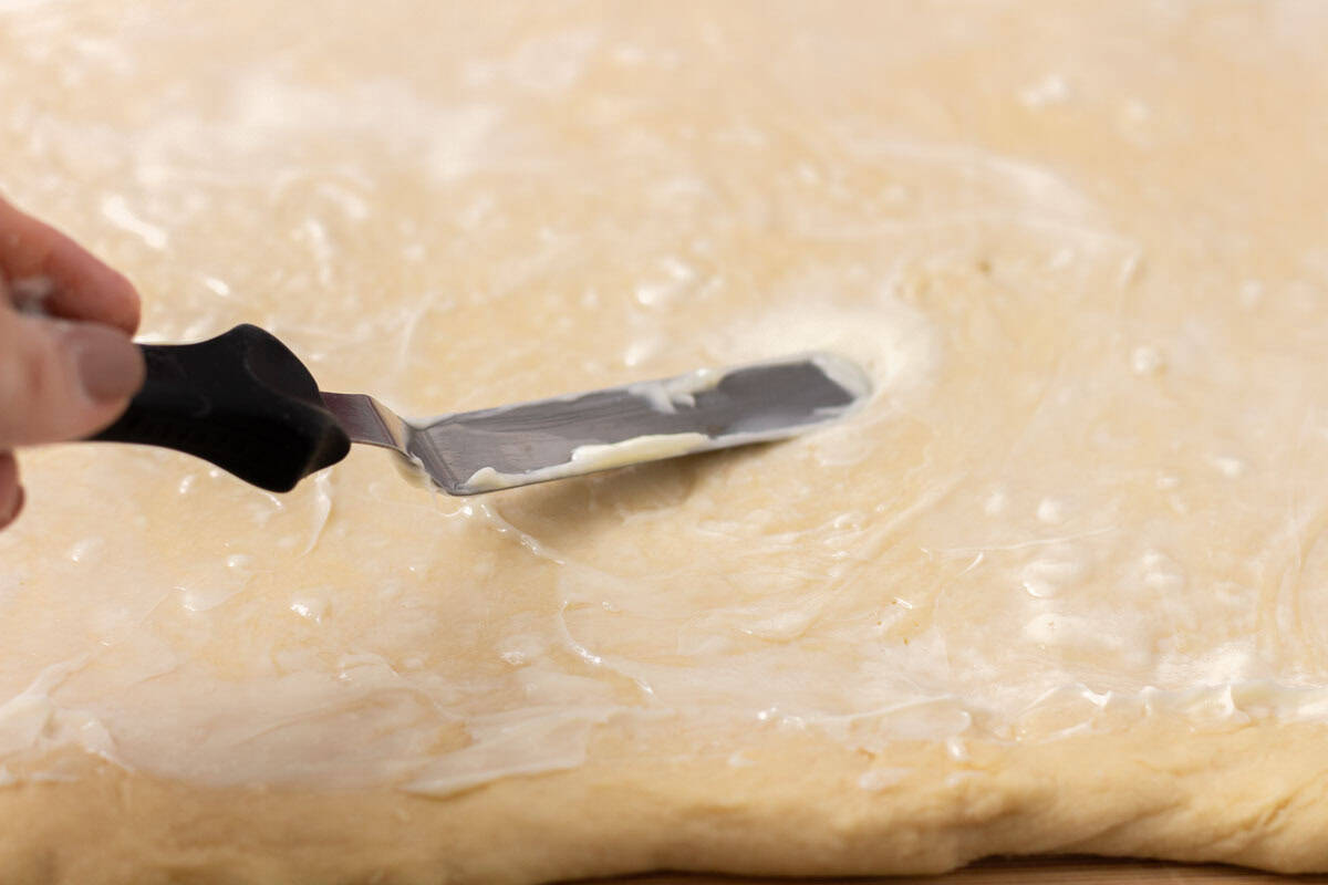 Sour Dough Discard Cinnamon Rolls | thewendthousekitchen.com Spreading softened butter on cinnamon roll dough with an offset spatula.
