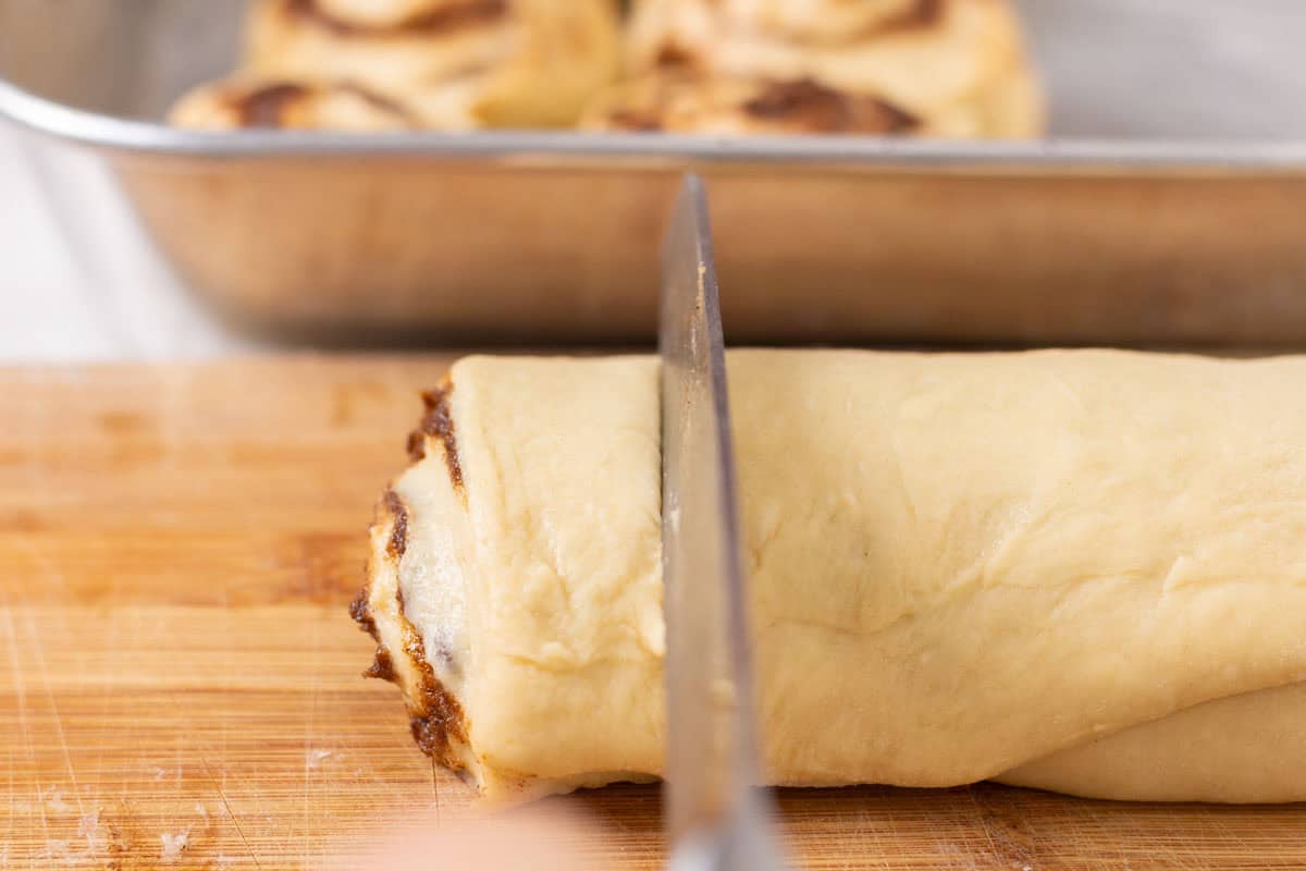Sour Dough Discard Cinnamon Rolls | thewendthousekitchen.com Cutting cinnamon rolls from a log of cinnamon roll dough.