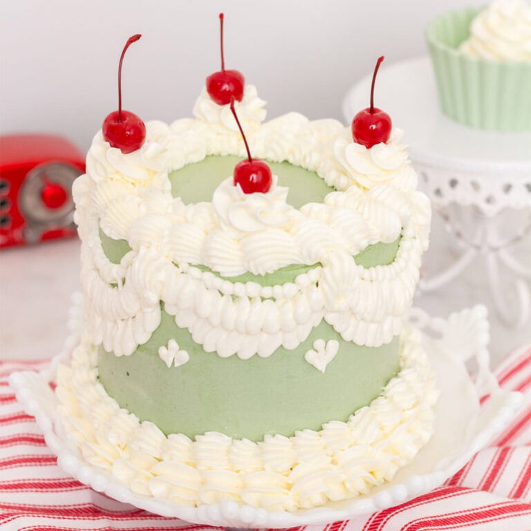 Decorated green and white lambeth WASC cake with cherries on top.