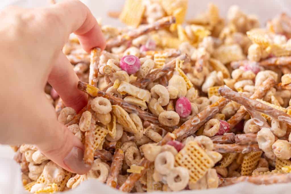 Valentine Bait Snack Mix | thewendthousekitchen.com Breaking up snack mix with hands.