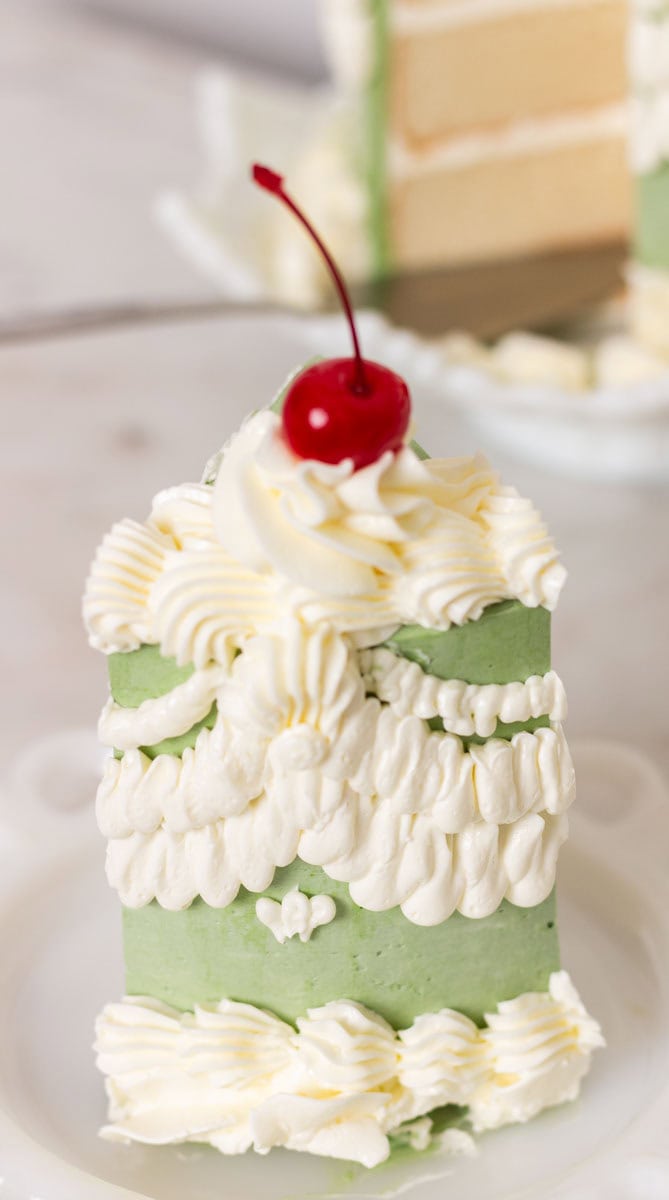 How To Make Italian Meringue Buttercream | thewendthousekitchen.com The back of a piece of cake heavily decorated with Italian meringue buttercream and topped with a marschino cherry.