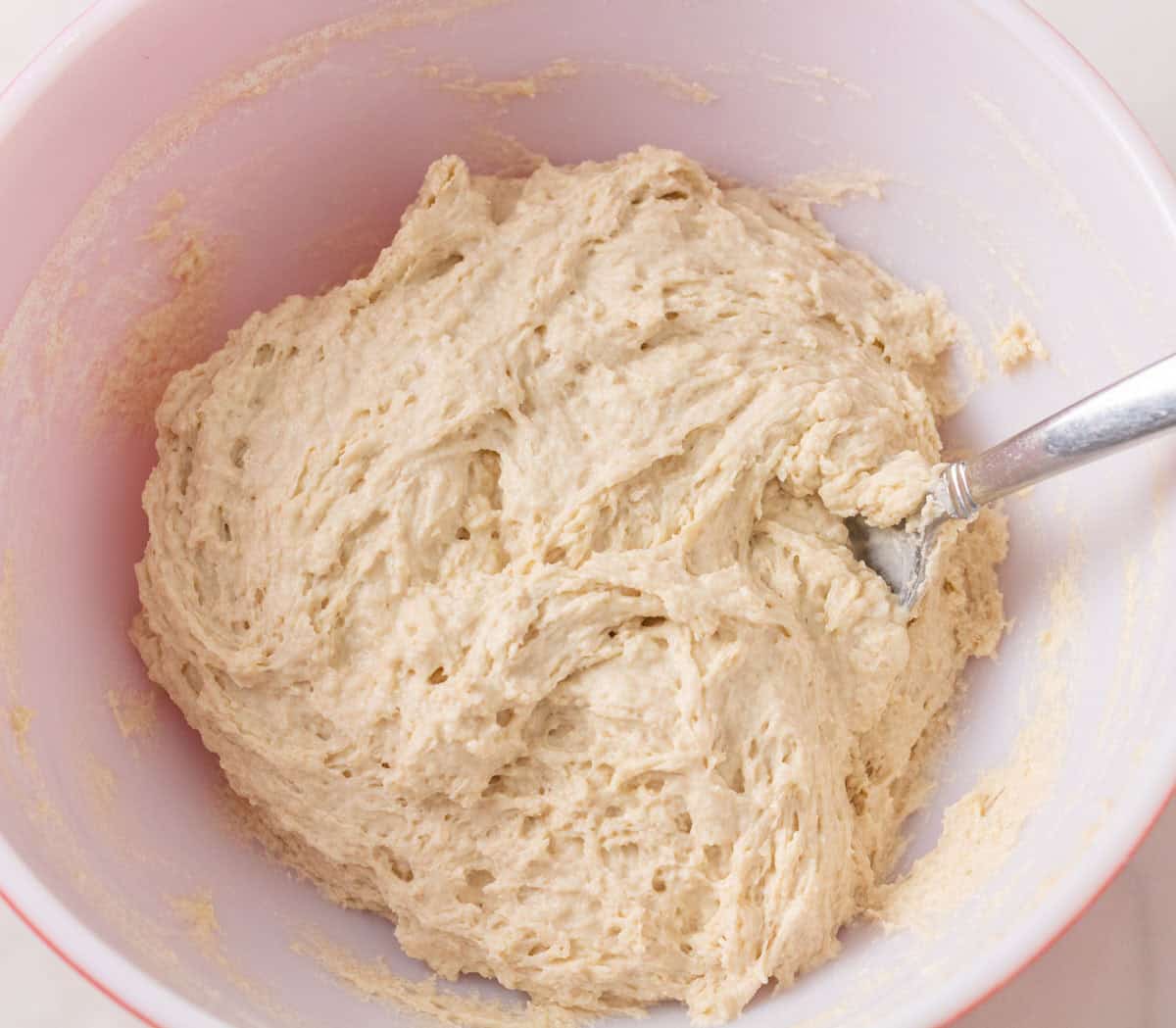 Sourdough Discard English Muffin Recipe | thewendthousekitchen.com Sourdough discard, milk, sugar, flour and butter combined in a large mixing bowl with a large spoon.