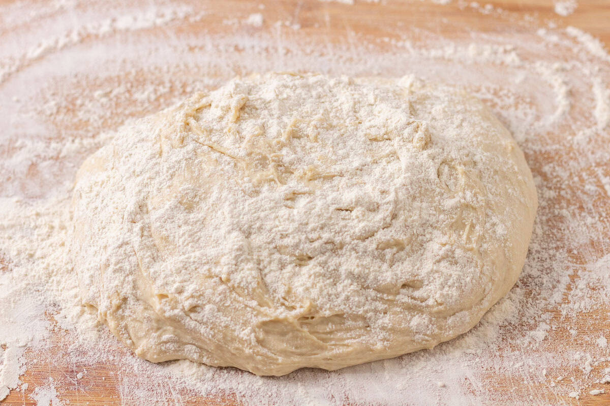 Sourdough Discard English Muffin Recipe | thewendthousekitchen.com English muffin dough turned out onto a floured wooden cutting board with flour sprinkled over the top of the dough.