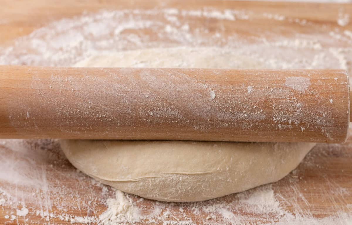 Sourdough Discard English Muffin Recipe | thewendthousekitchen.com Rolling our English muffin dough onto a wooden cutting board with a wooden rolling pin.