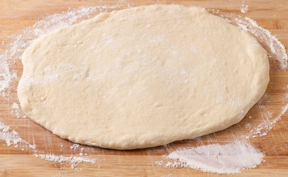 Sourdough Discard English Muffin Recipe | thewendthousekitchen.com English muffin dough rolled out to 3/4-inch thick on a wooden cutting board.